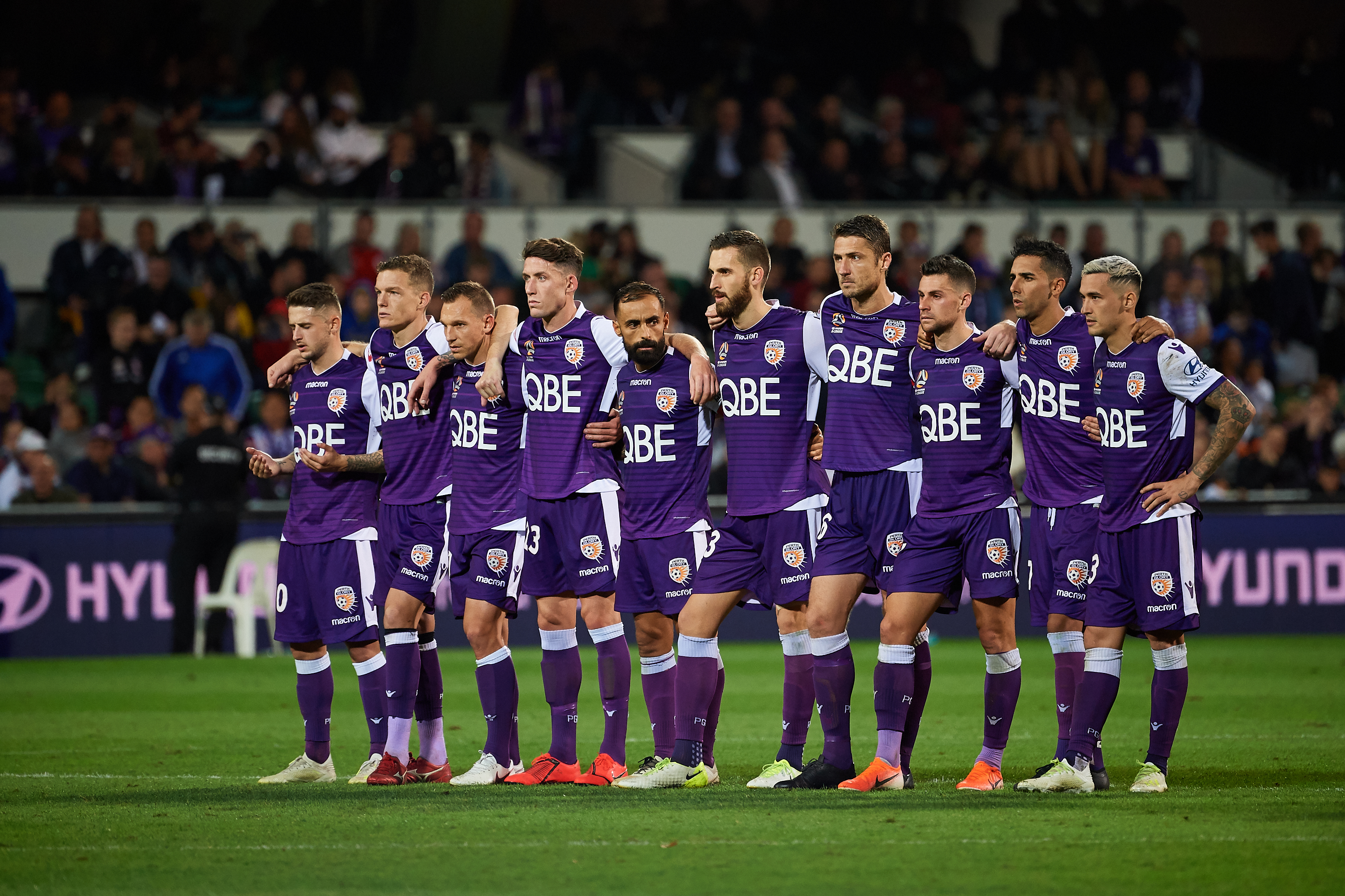 A photo of the Perth Glory football team standing on the pitch at Optus Stadium during an A League Grand Final