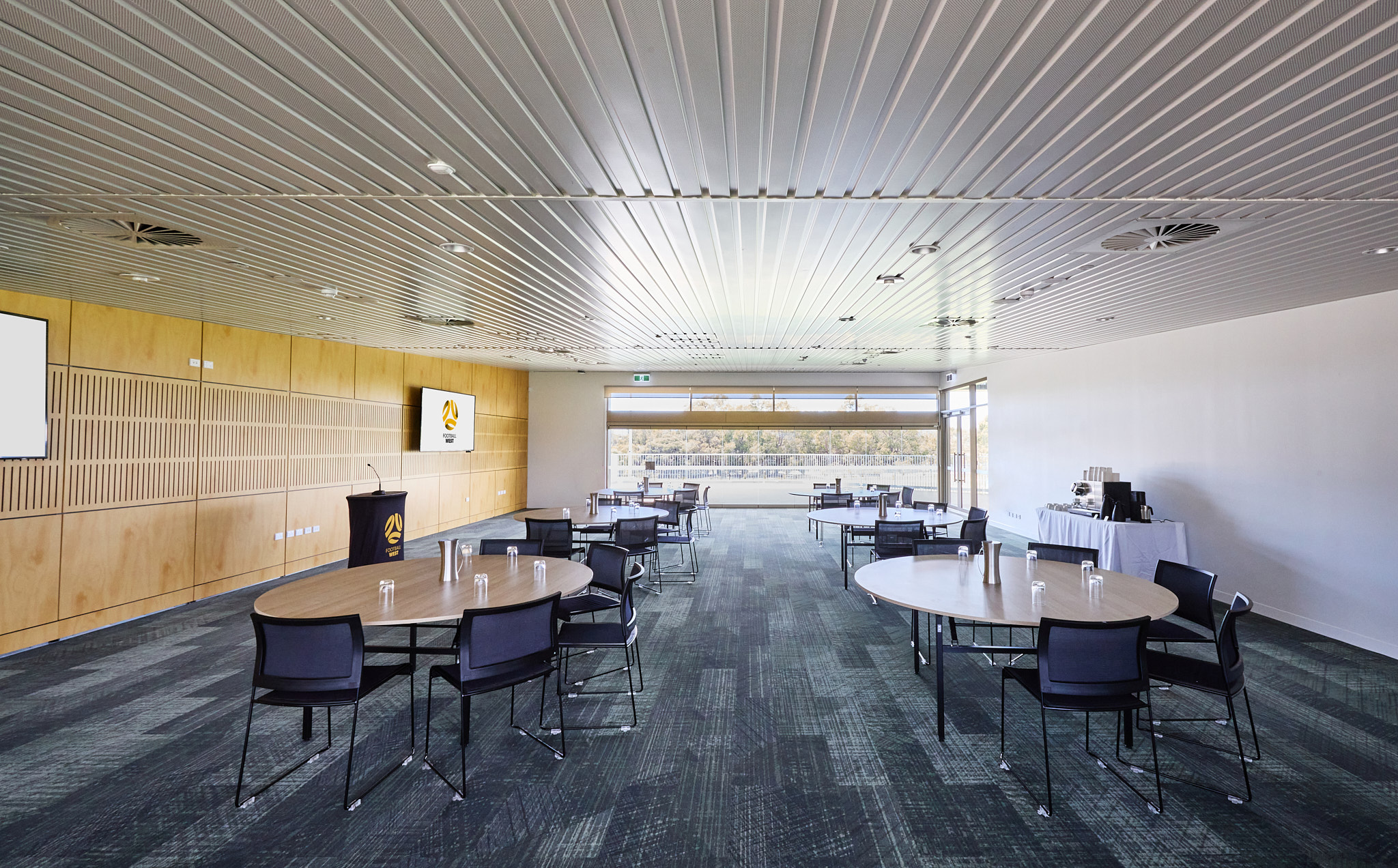 A photo of multiple tables set up around a lectern in a meeting room at the Sam Kerr Football Centre in Queens Park, Perth