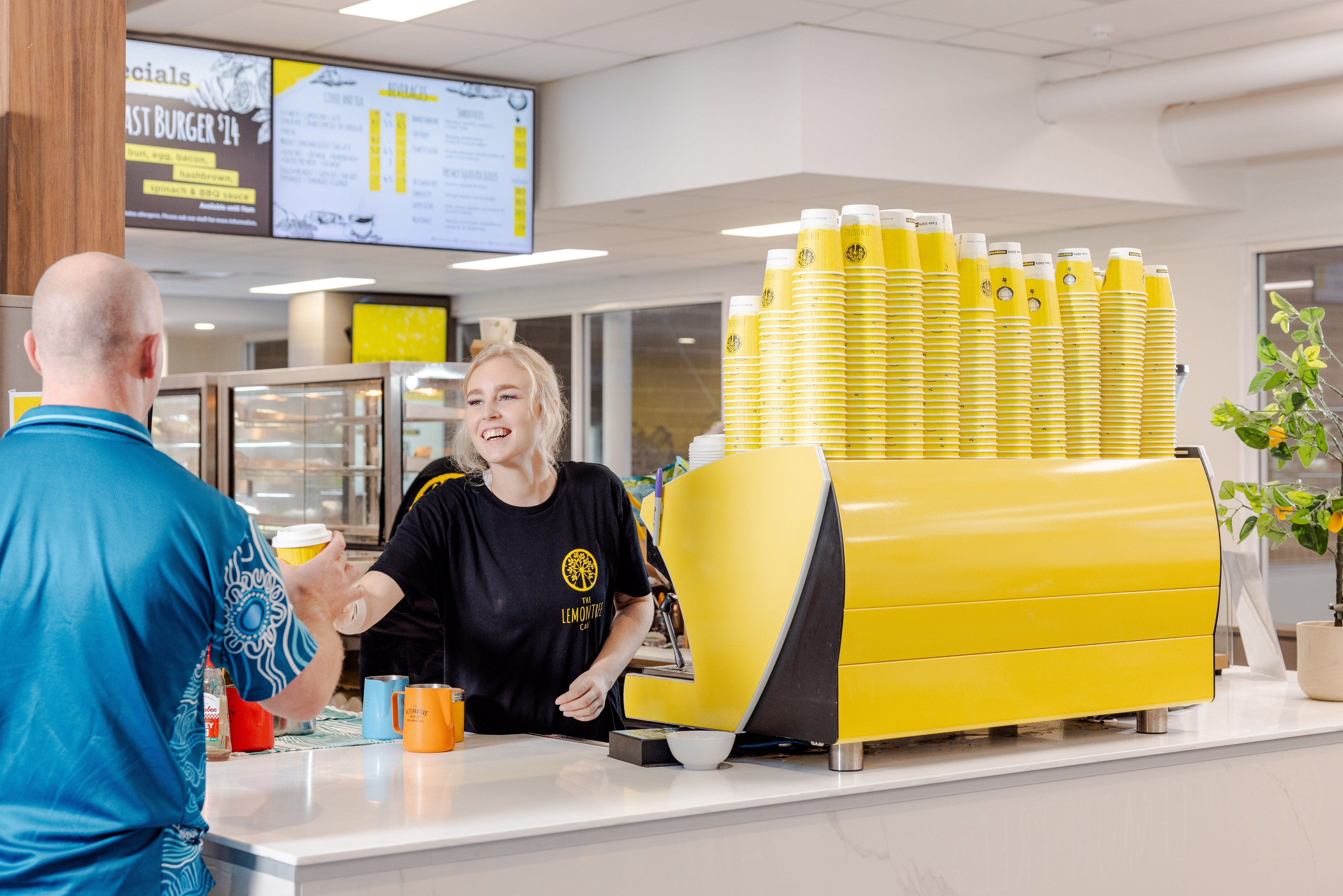A photo of a worker handing a customer a coffee at the Lemon Tree Cafe located inside Perth HPC