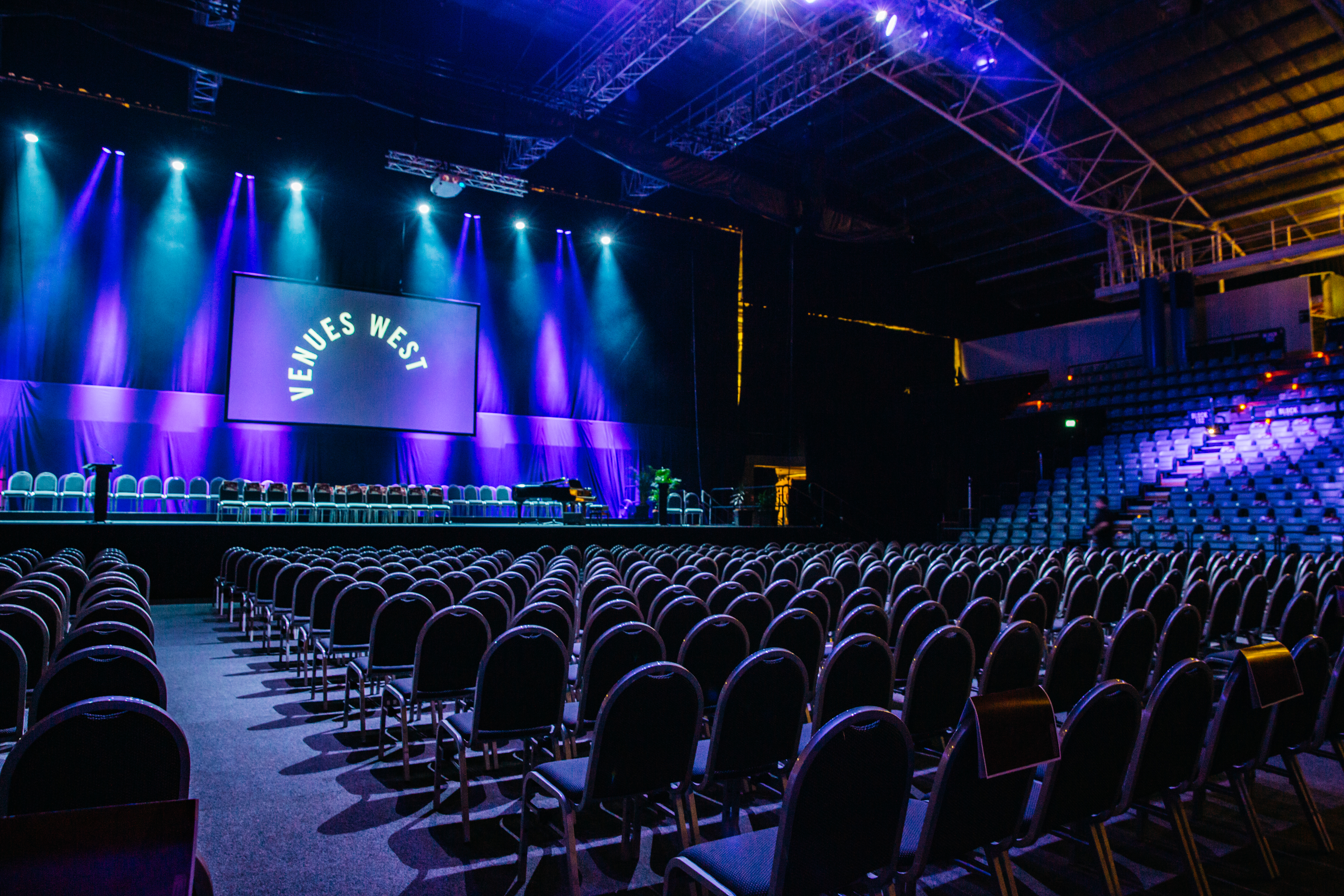 A photo of the main arena at Perth HPC, including rows of chairs and a lit up stage