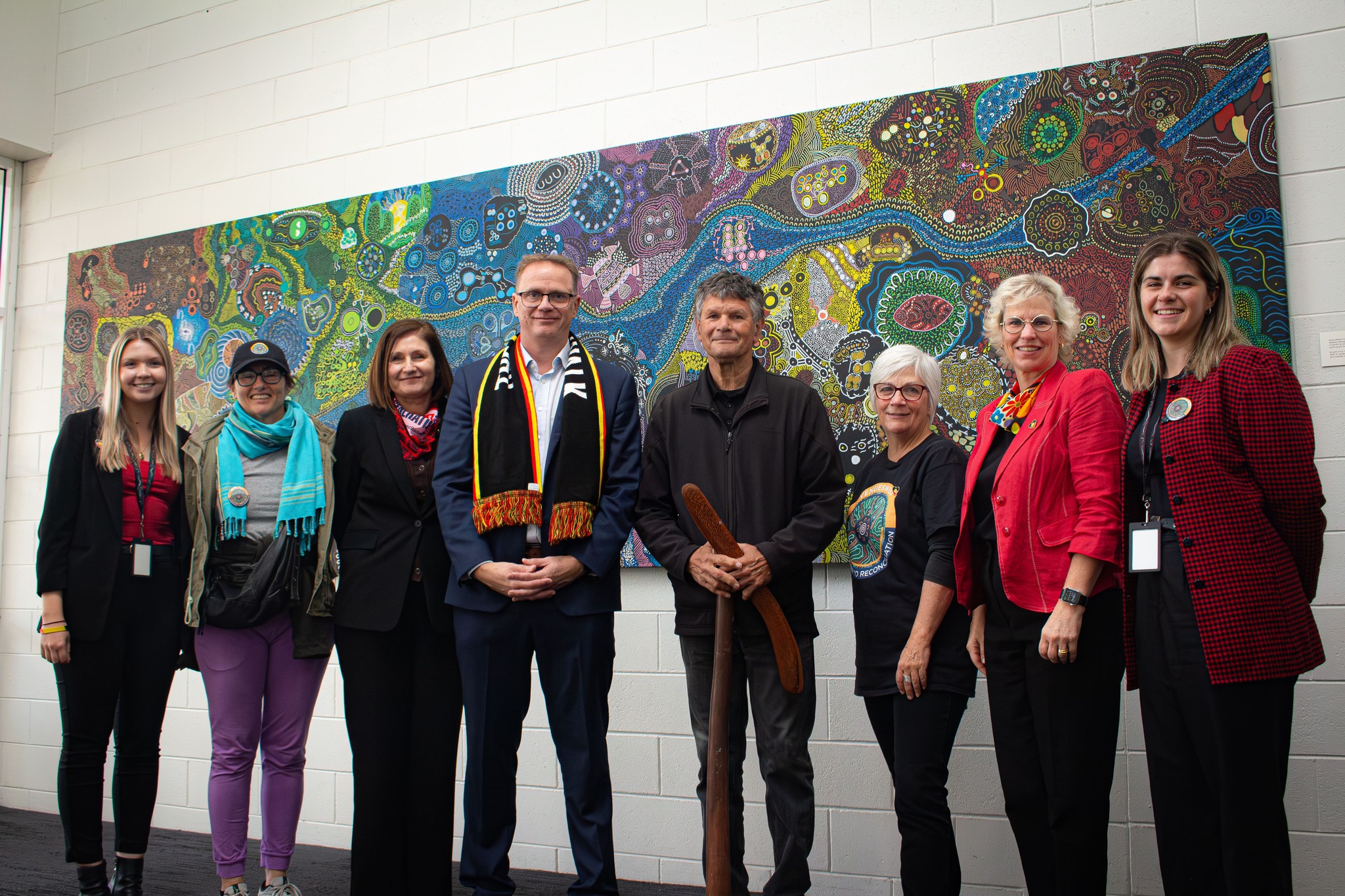 A photo of VenuesWest employees posing in front of Indigenous artwork