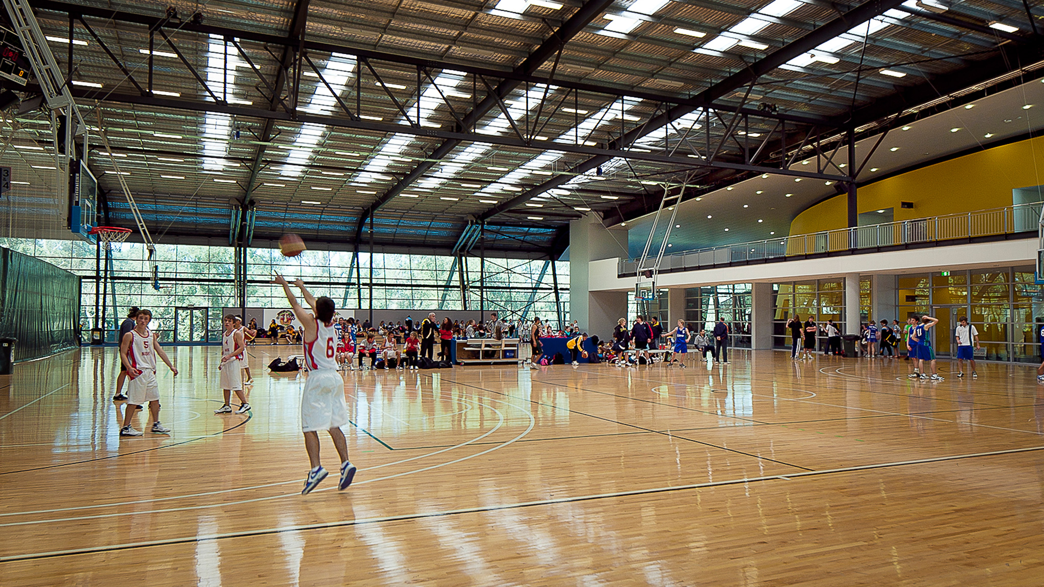 A photo of Perry Lakes Hawks basketball players warming up on court at the Bendat Basketball Centre