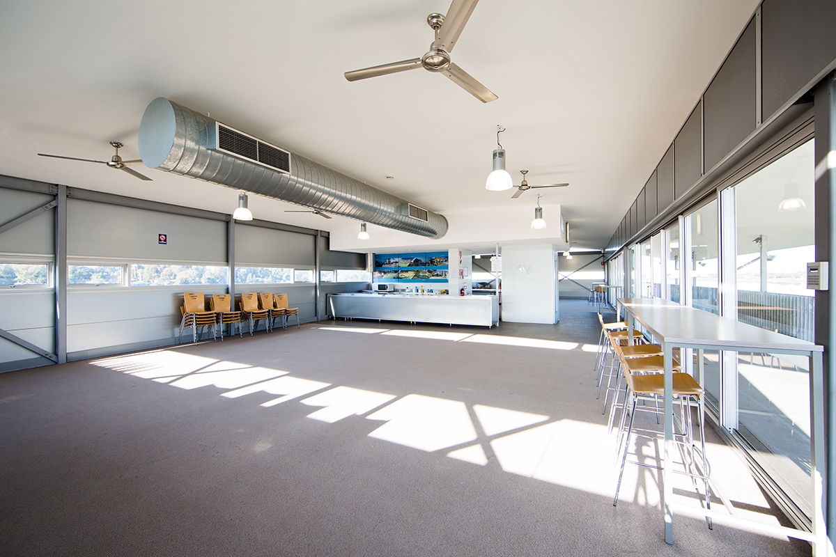 A photo of a function space, sporadic filled with chairs and a kitchen area, located at the Champion Lakes Regatta Centre