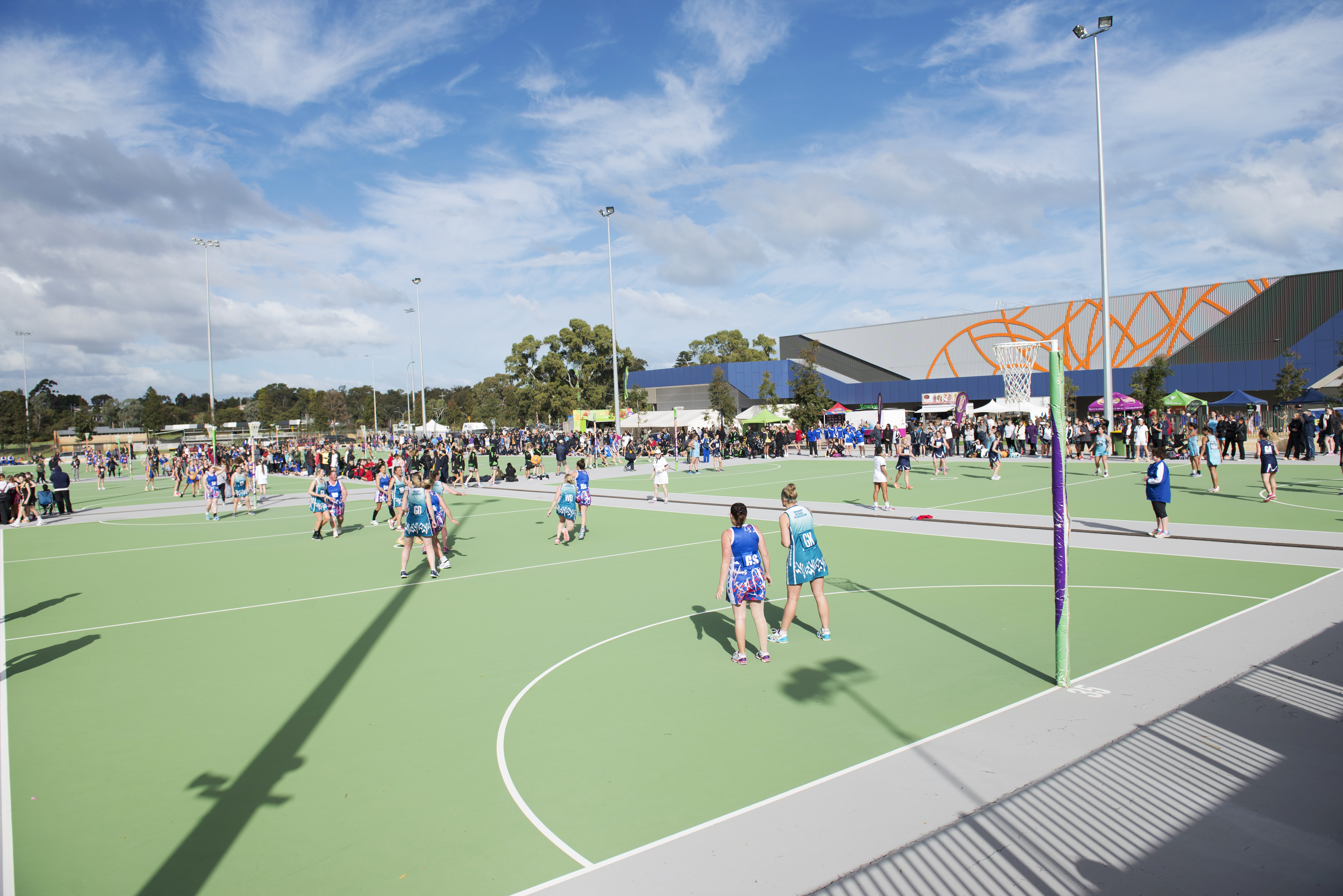 A photo of a game of netball being played on an outdoor court at the Gold Netball Centre in Jolimont, Perth