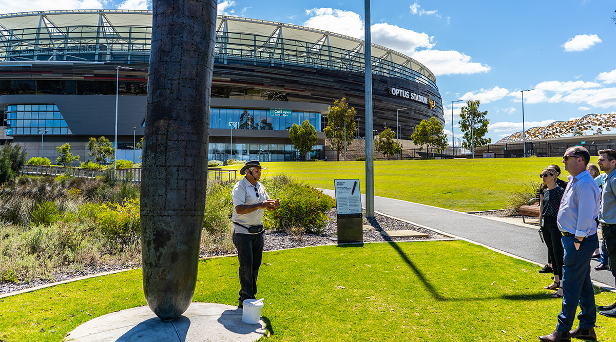 A photo of a man giving an Aboriginal cultural tour outside of Optus Stadium