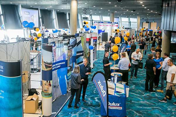 A photo of a conference with multiple stalls set up in an event space at Optus Stadium in Burswood, Perth