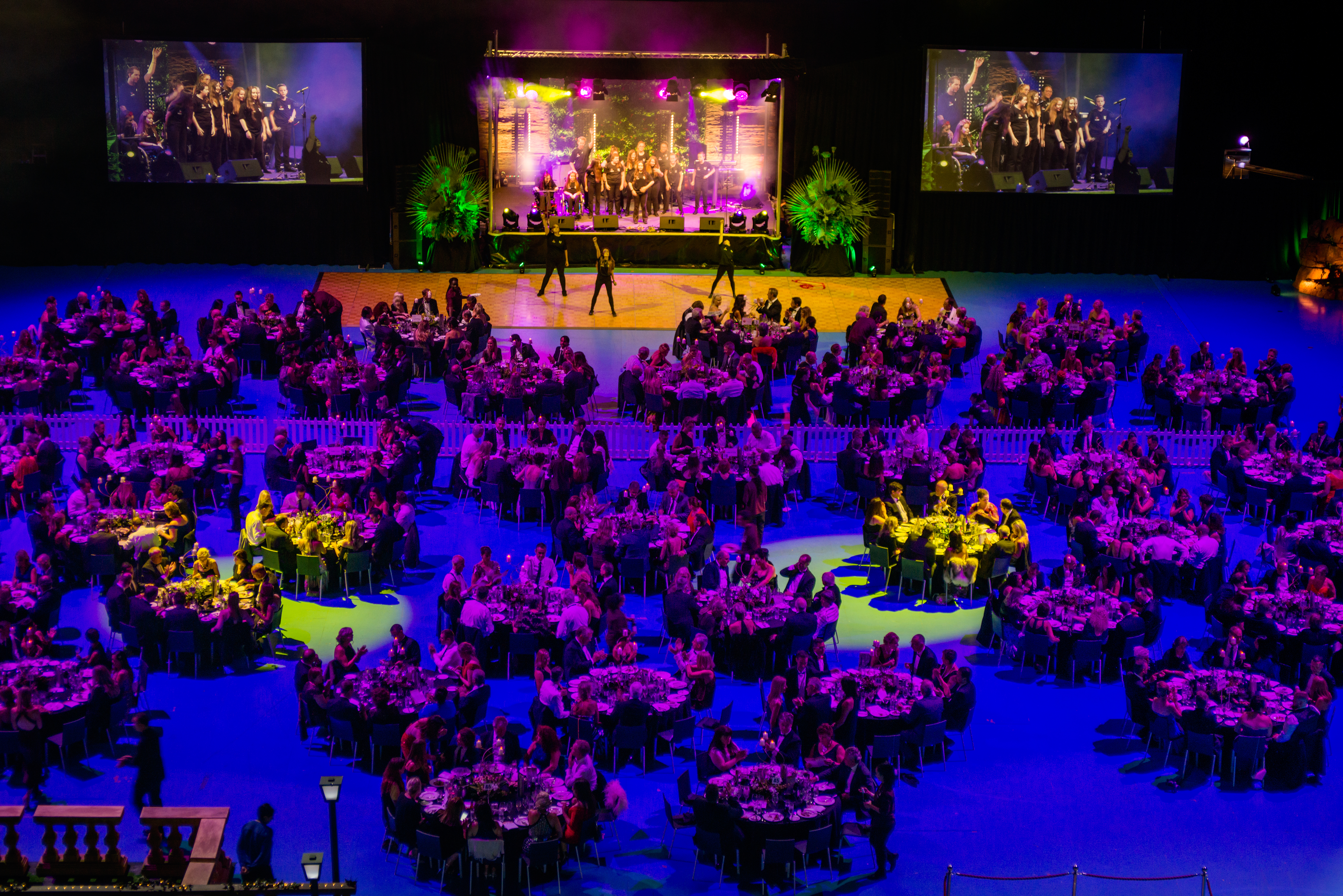 A photo of a function with tables and chairs with a stage performance at RAC Arena in Perth