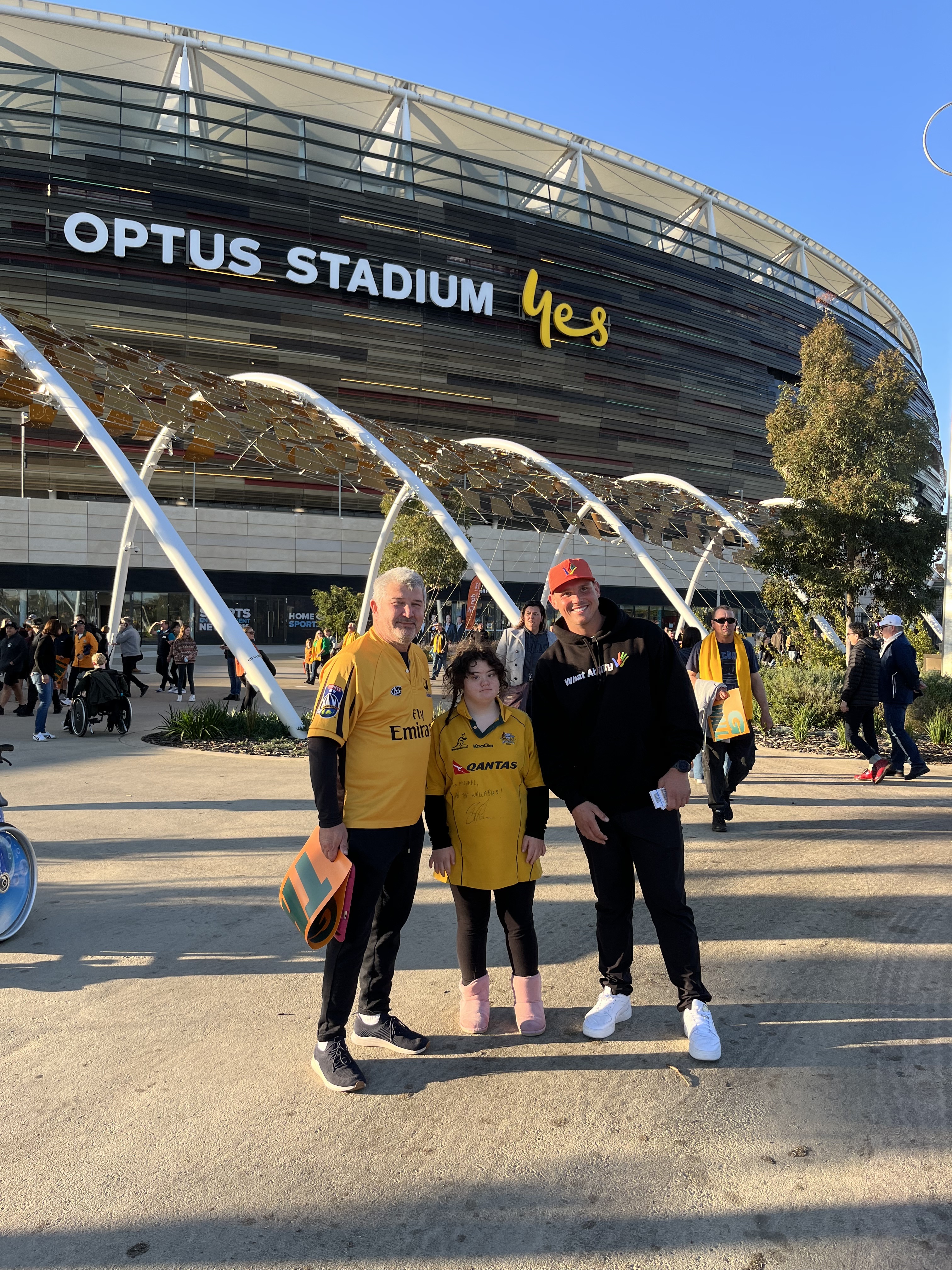 A photo of three people posing for a photo outside of Optus Stadium
