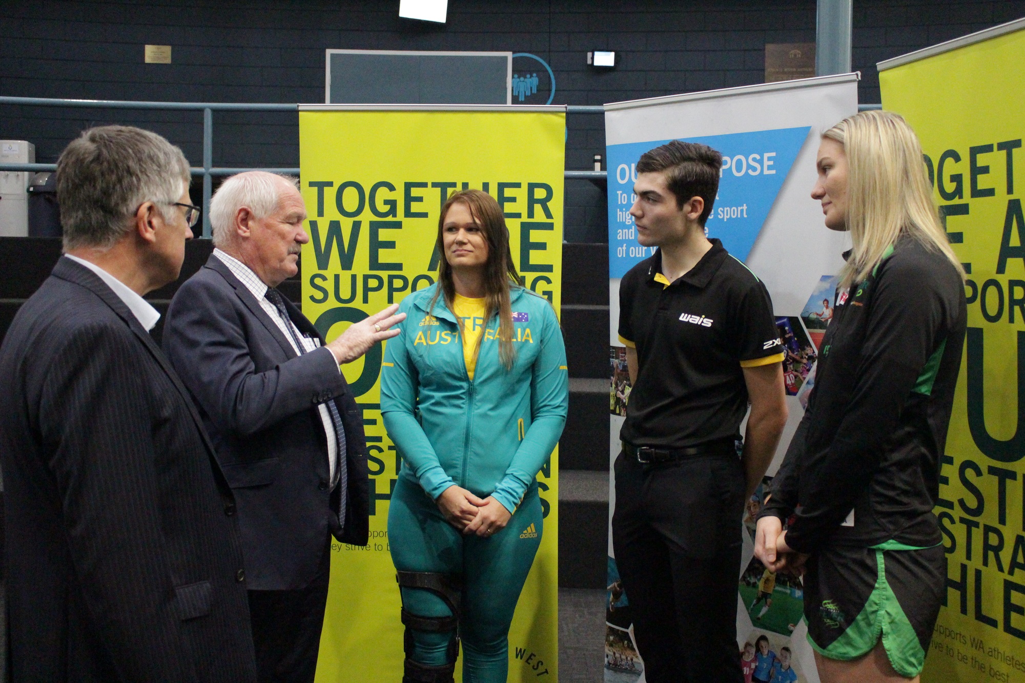 Photo of two men in suits talking to three VenuesWest brand ambassadors