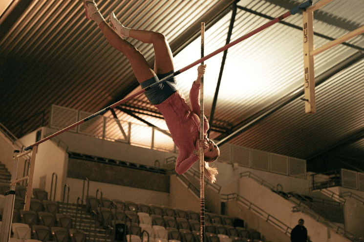 Photo of Maddi Lawson pole vaulting over the bar as part of the Just Add Venue brand campaign
