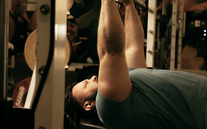 Close up photo of Ben Wright bench pressing weights as part of the Just Add Venue brand campaign