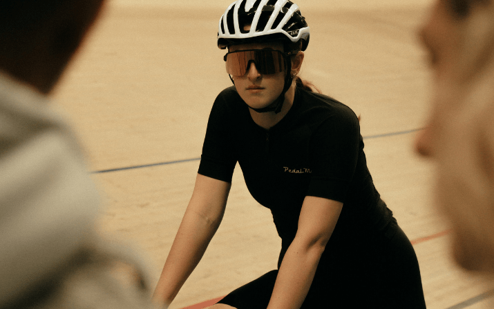 Close up photo of Isla Carr on a race bike wearing googles and a helmet at the track cycling Speed Dome in Midvale, Perth