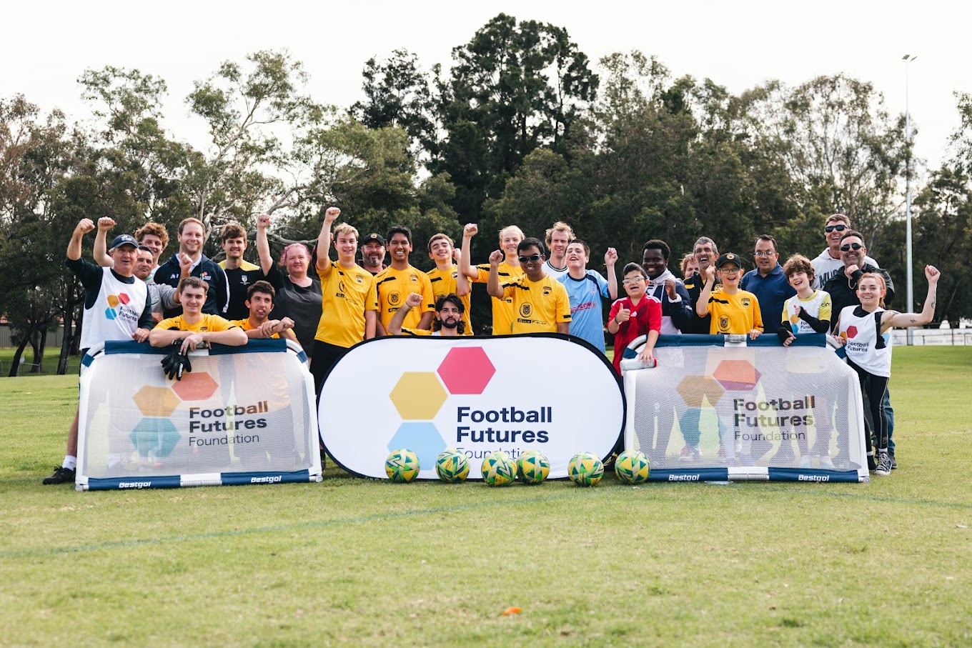A photo of multiple people standing behind signs that say Football Futures Foundation on a grassed area